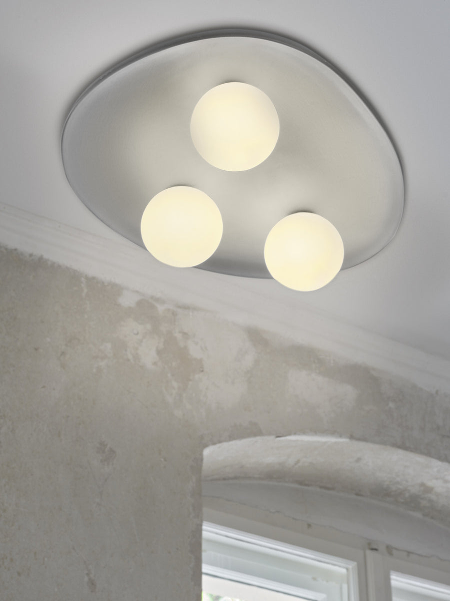 Détail de près sous plafond, trois globes lumineux et finition plâtre blanc