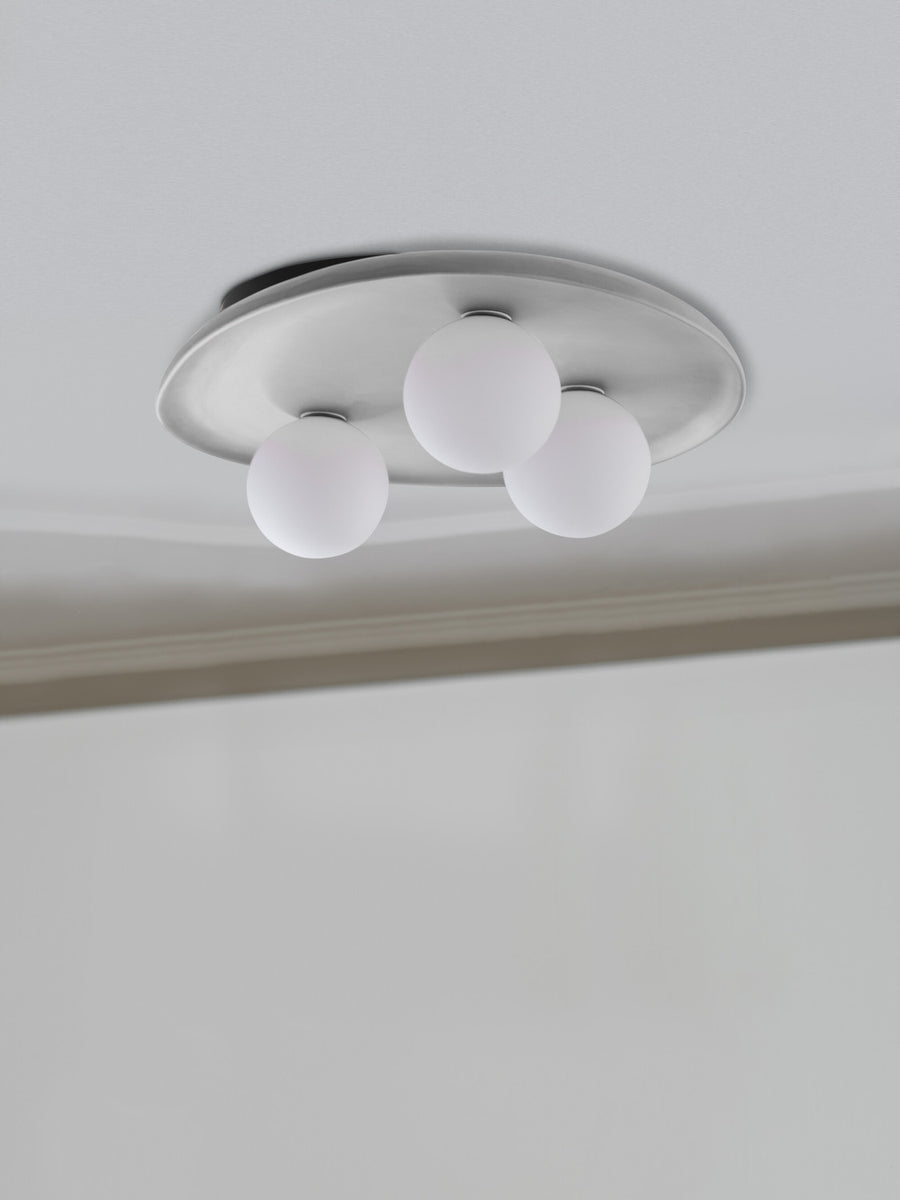 Vue rapprochée du plafonnier fixé au plafond, plateau ovale et trois globes blancs