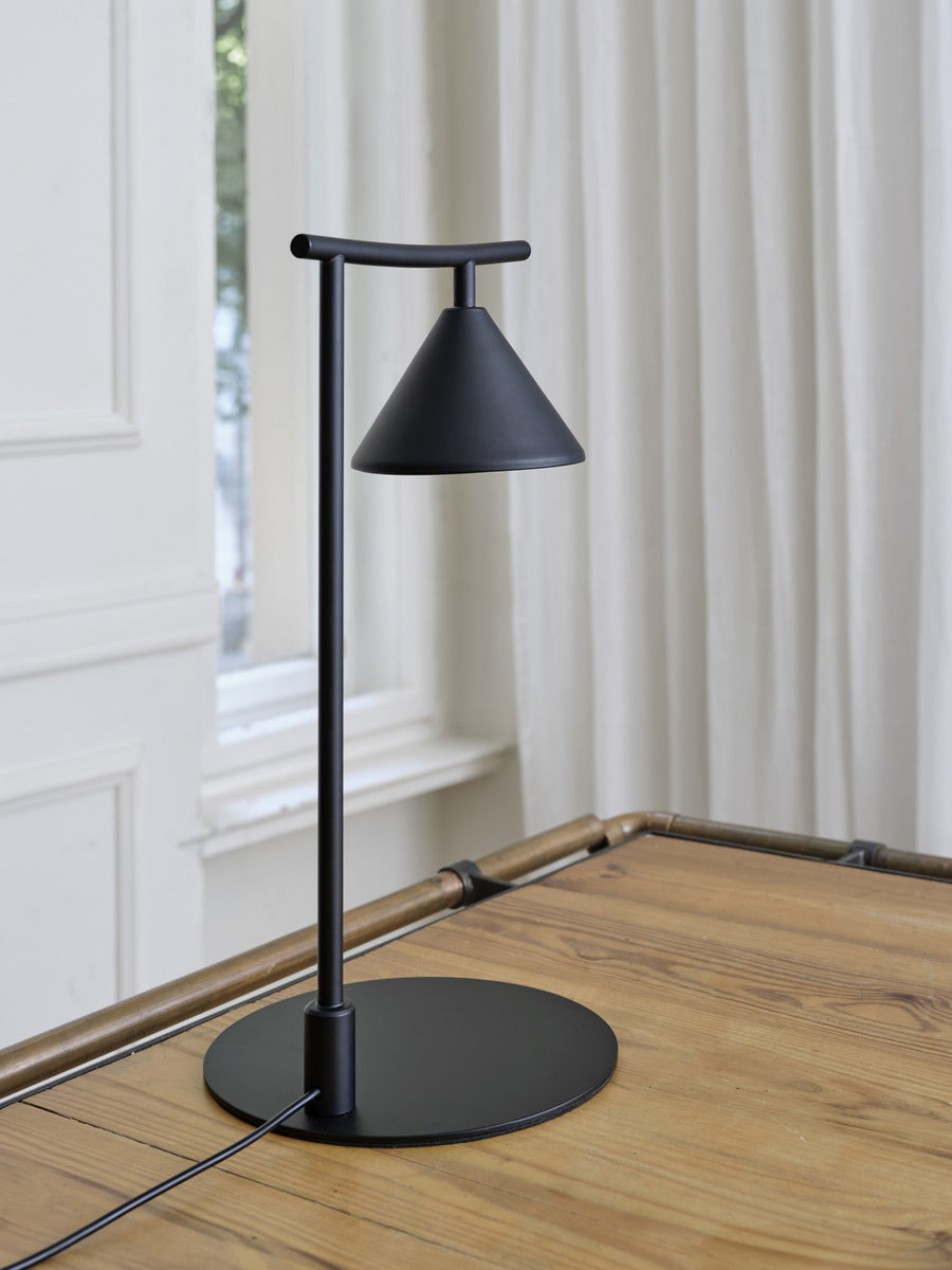 Détail de la base ronde et du pied fin sur table en bois clair.