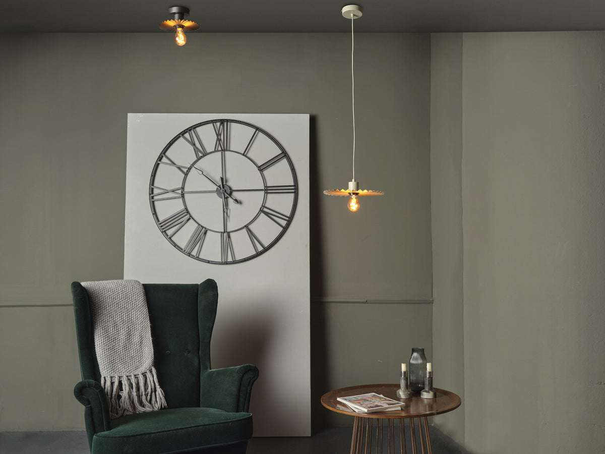 Mise en ambiance avec plafonnier, fauteuil vert, horloge murale et table basse.