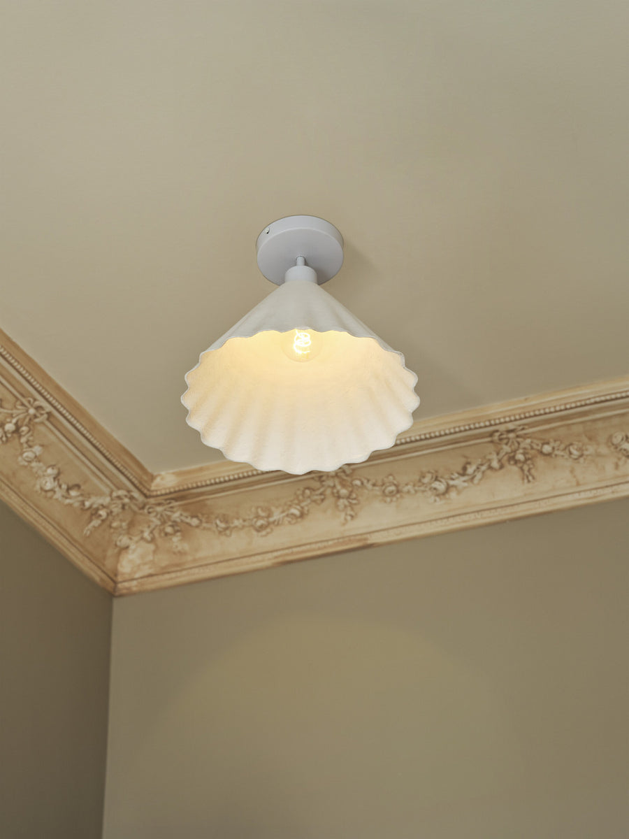 Vue en contre-plongée du plafonnier allumé près d'une moulure décorative.