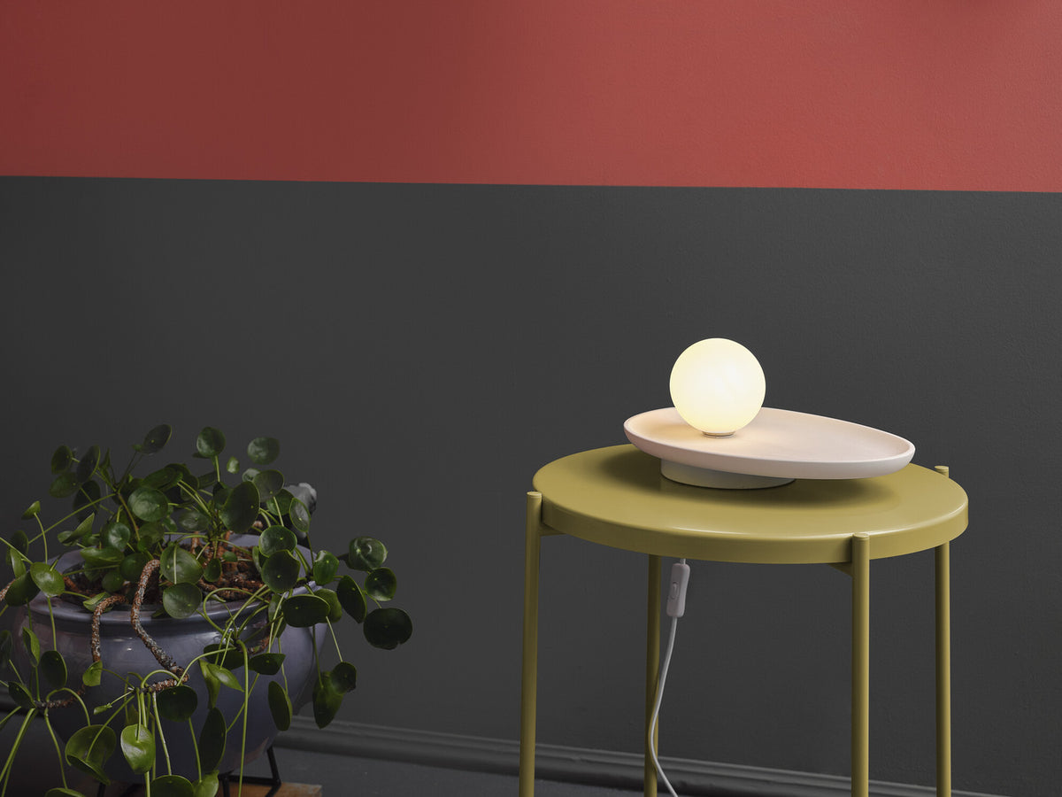 Mise en ambiance sur table jaune, lampe allumée près d'une plante verte