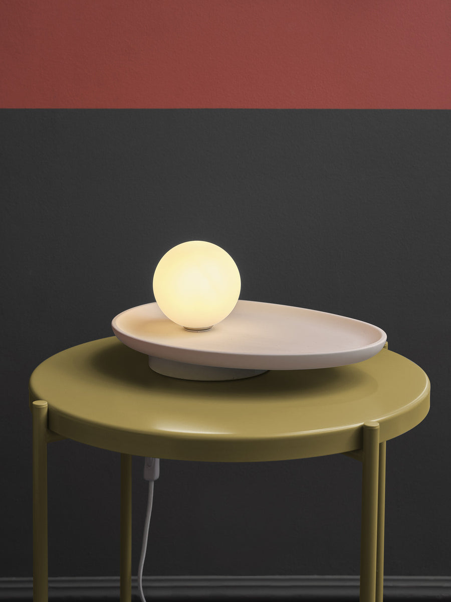 Gros plan de la lampe allumée posée sur une table jaune devant mur bicolore