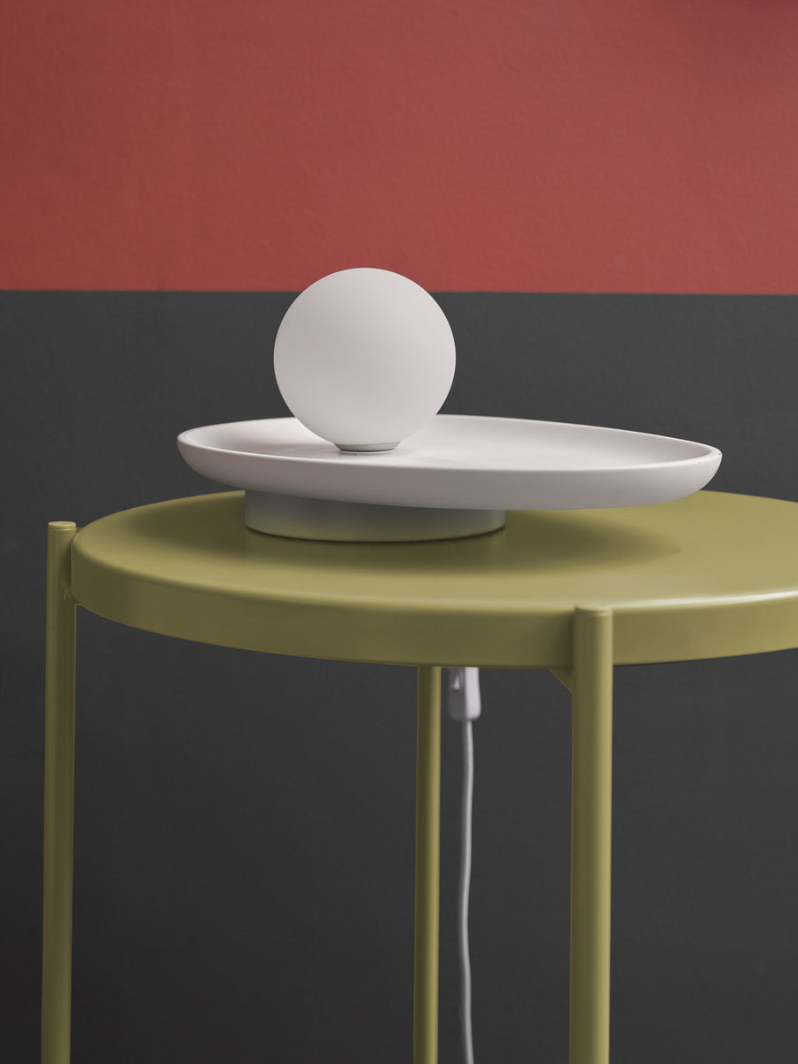 Détail du globe blanc éteint et du plateau ovale sur table vert olive