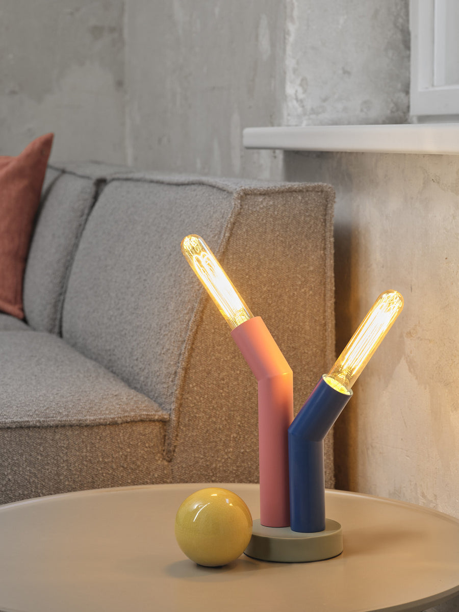 Vue rapprochée de la lampe allumée avec ampoules dorées, boule jaune et canapé flou.