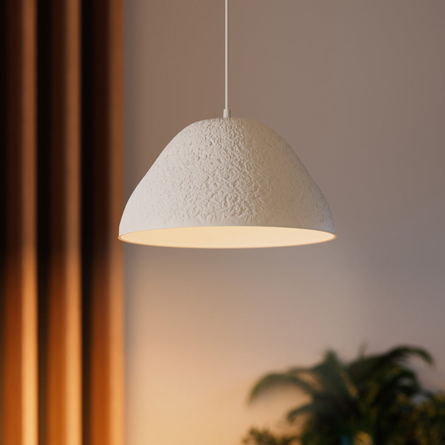 Gros plan sur l'abat-jour texturé blanc et sa lumière chaude, près d'un rideau.