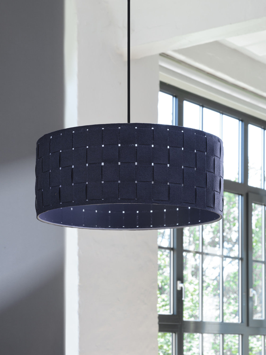 Suspension noire devant une fenêtre, montrant le motif tressé et le câble fin.