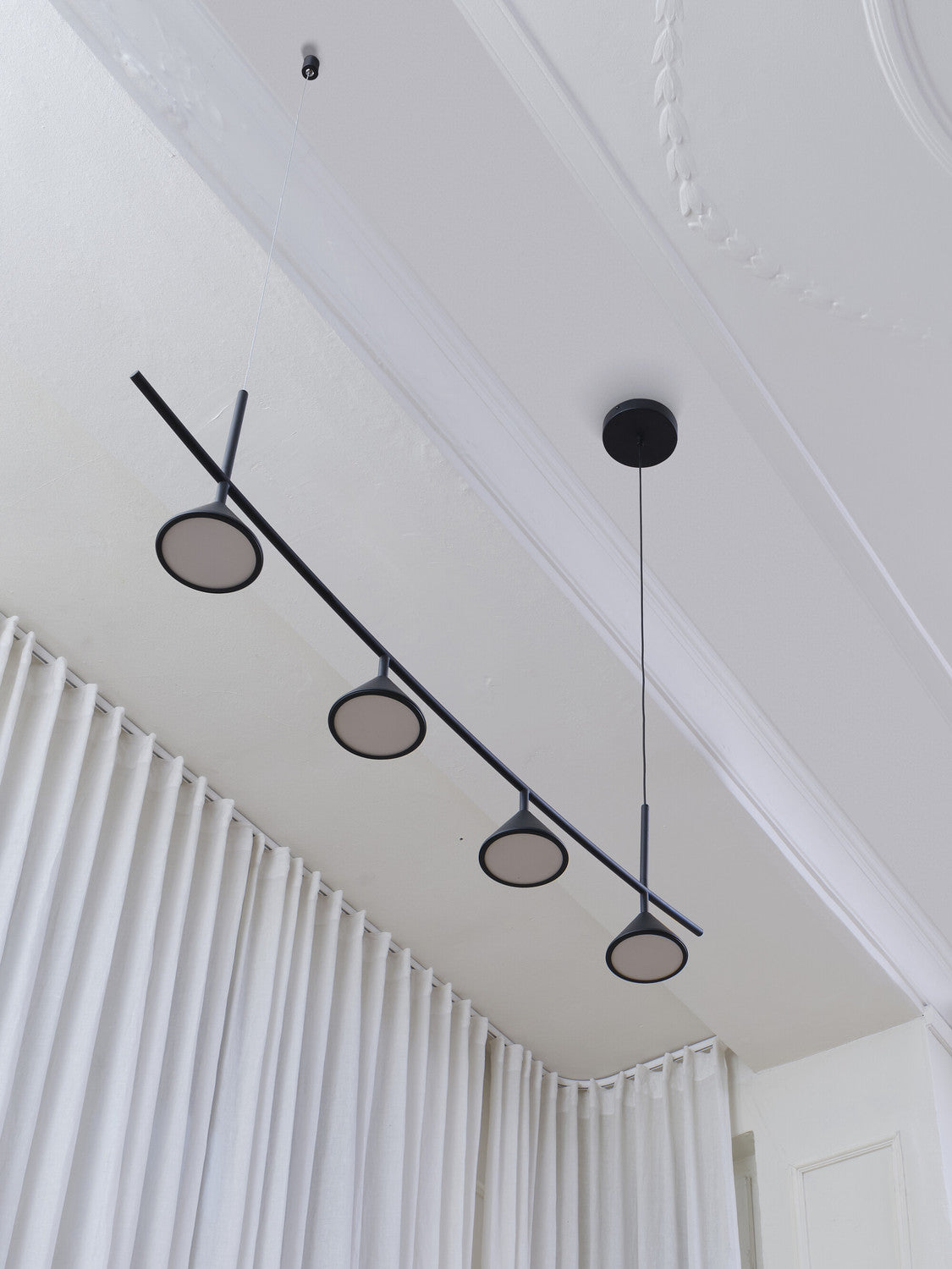 Vue en contre-plongée montrant les câbles et fixations au plafond, barre noire et quatre cônes.
