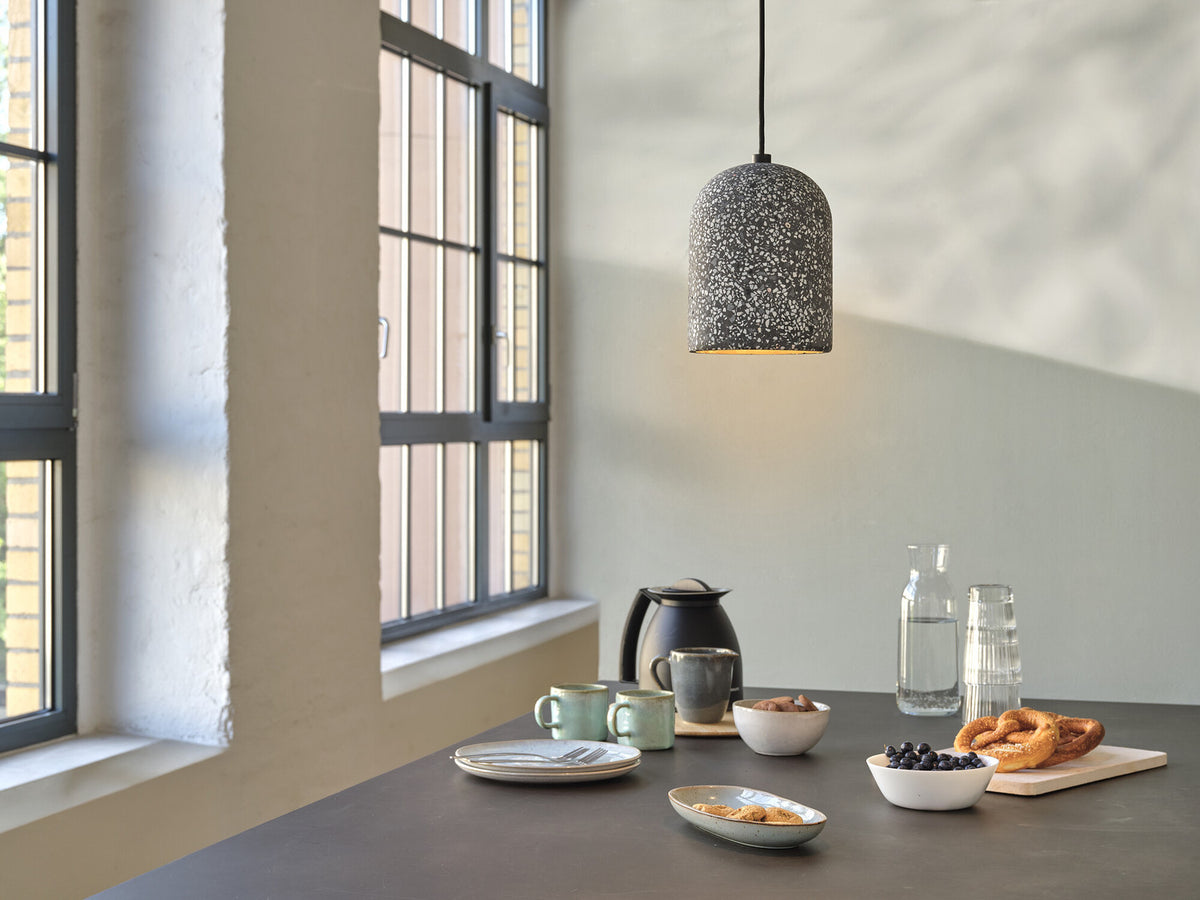 Mise en ambiance au-dessus d’une table de cuisine, suspension terrazzo allumée.