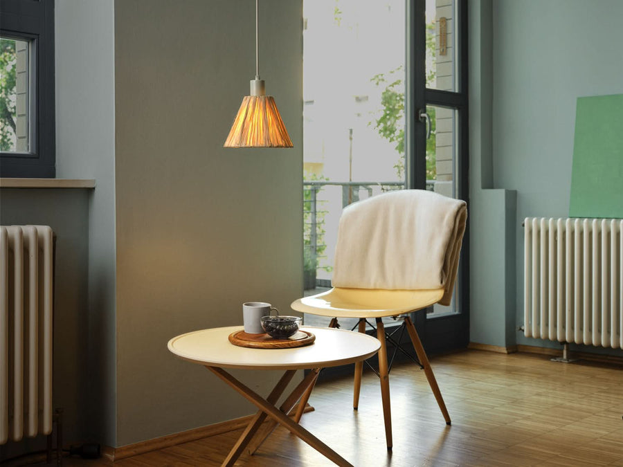 Suspension éclairée au-dessus d'une petite table près d'une fenêtre et d'un radiateur.