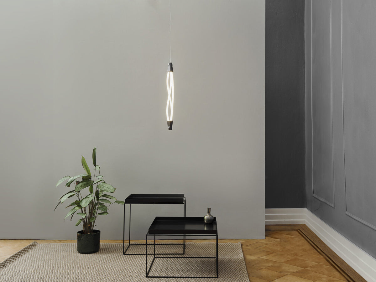 Suspension allumée dans un salon minimaliste avec plante et tables basses