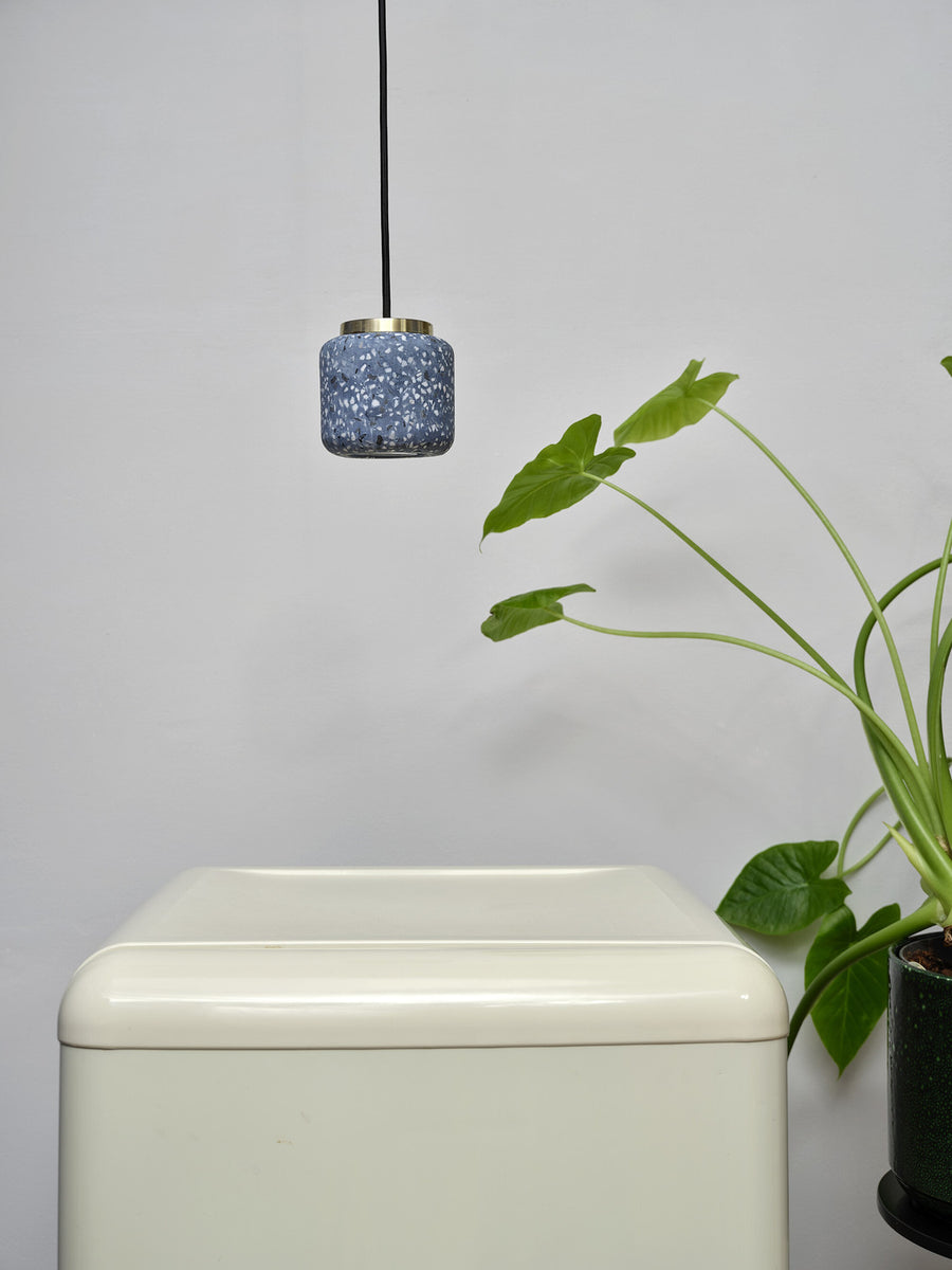 Suspension bleue installée au-dessus d'un meuble blanc près d'une plante verte