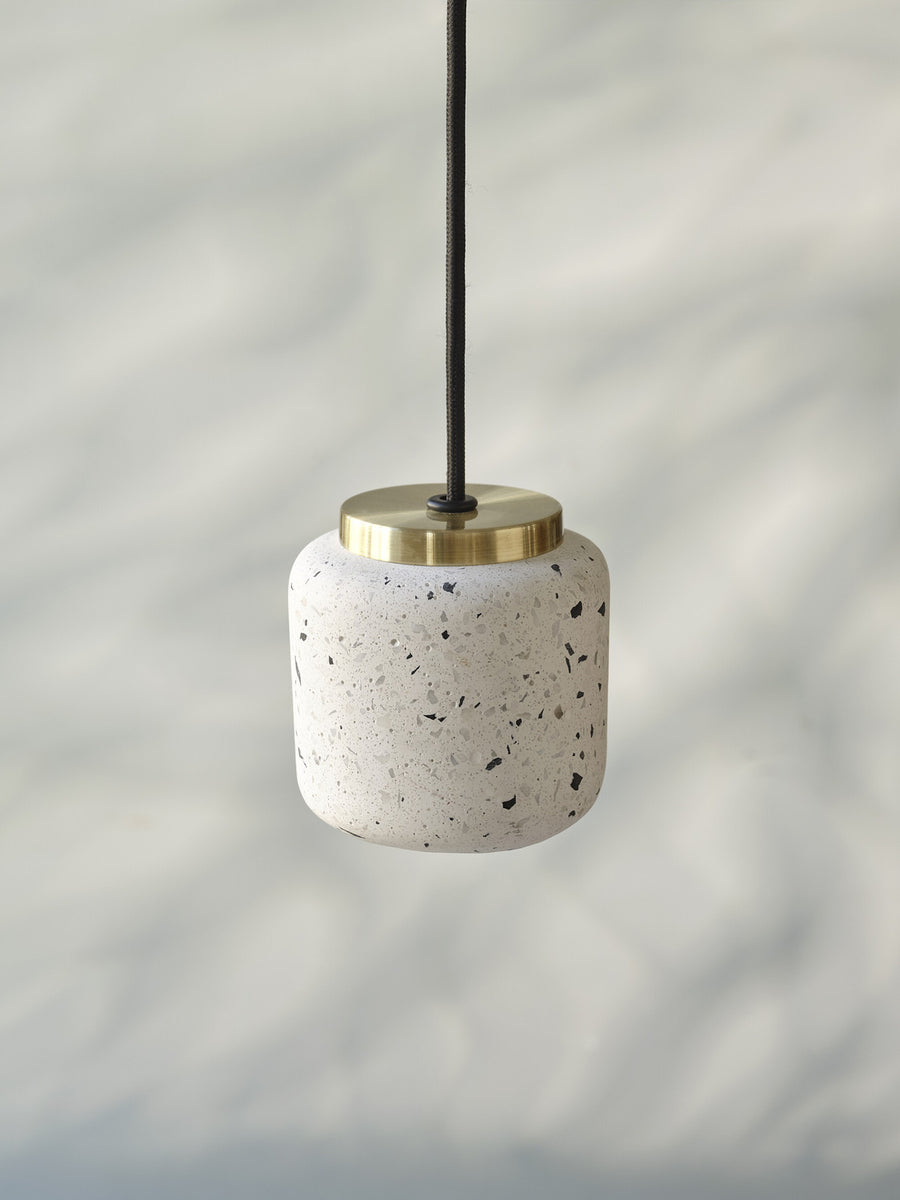 Gros plan sur la texture terrazzo et la bague en laiton de la suspension.