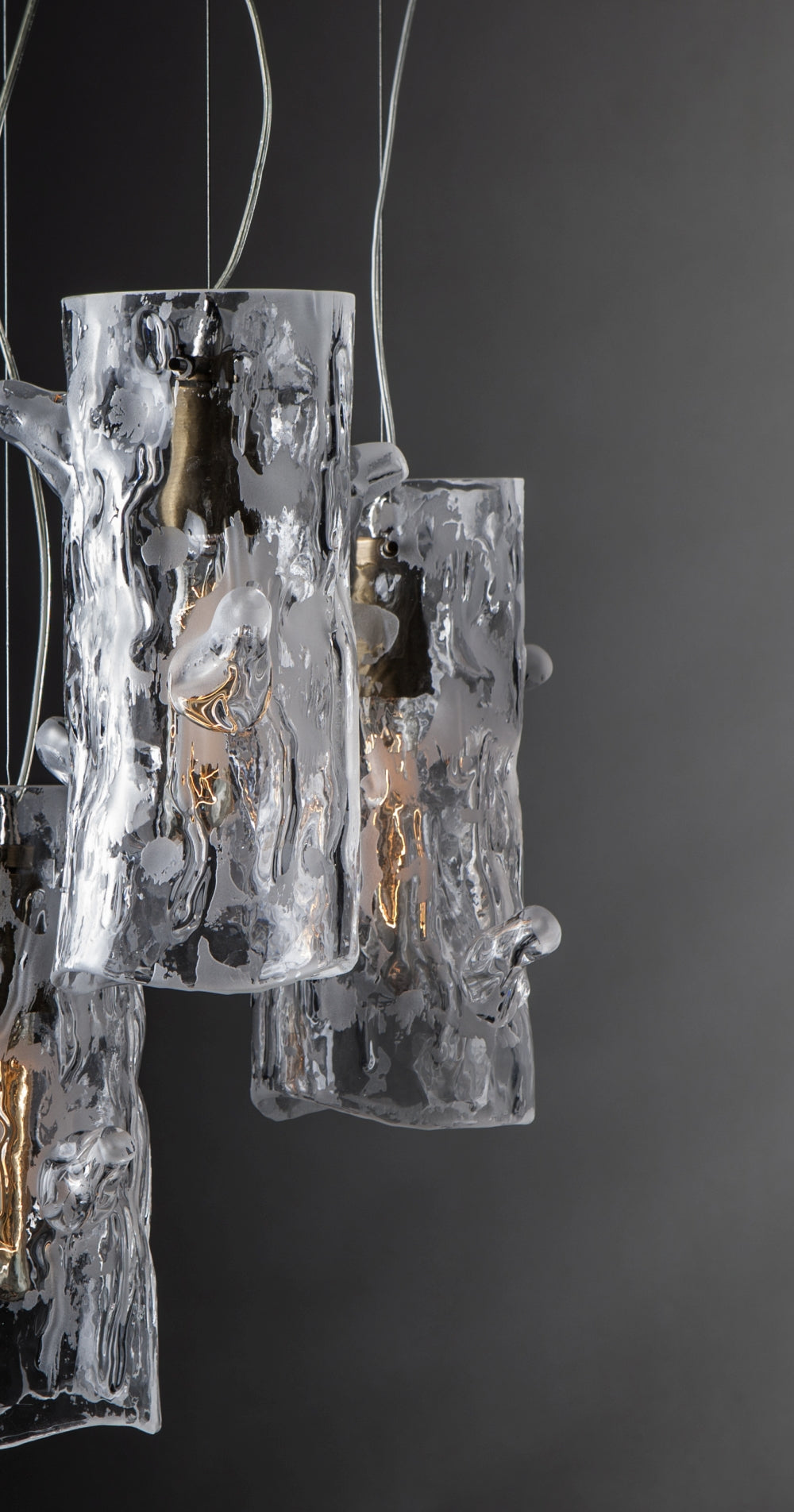 Vue de côté des cylindres de verre moulé suspendus par câbles fins sur fond gris