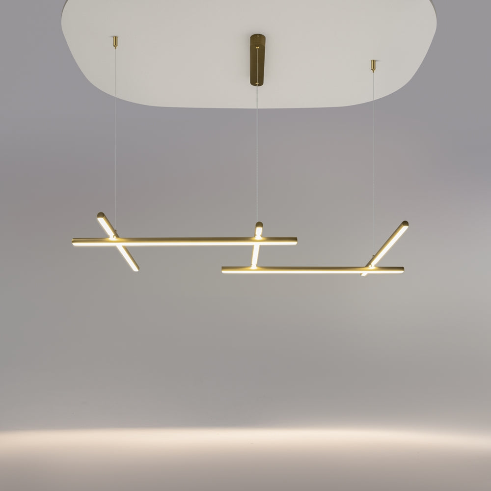 Luminaire suspendu allumé au plafond, structure dorée entrecroisée dans une pièce claire.