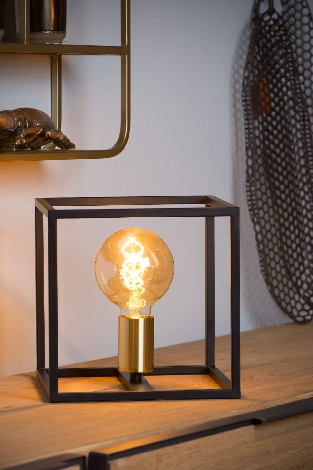 Mise en ambiance : lampe allumée sur meuble bois près d'un miroir rond