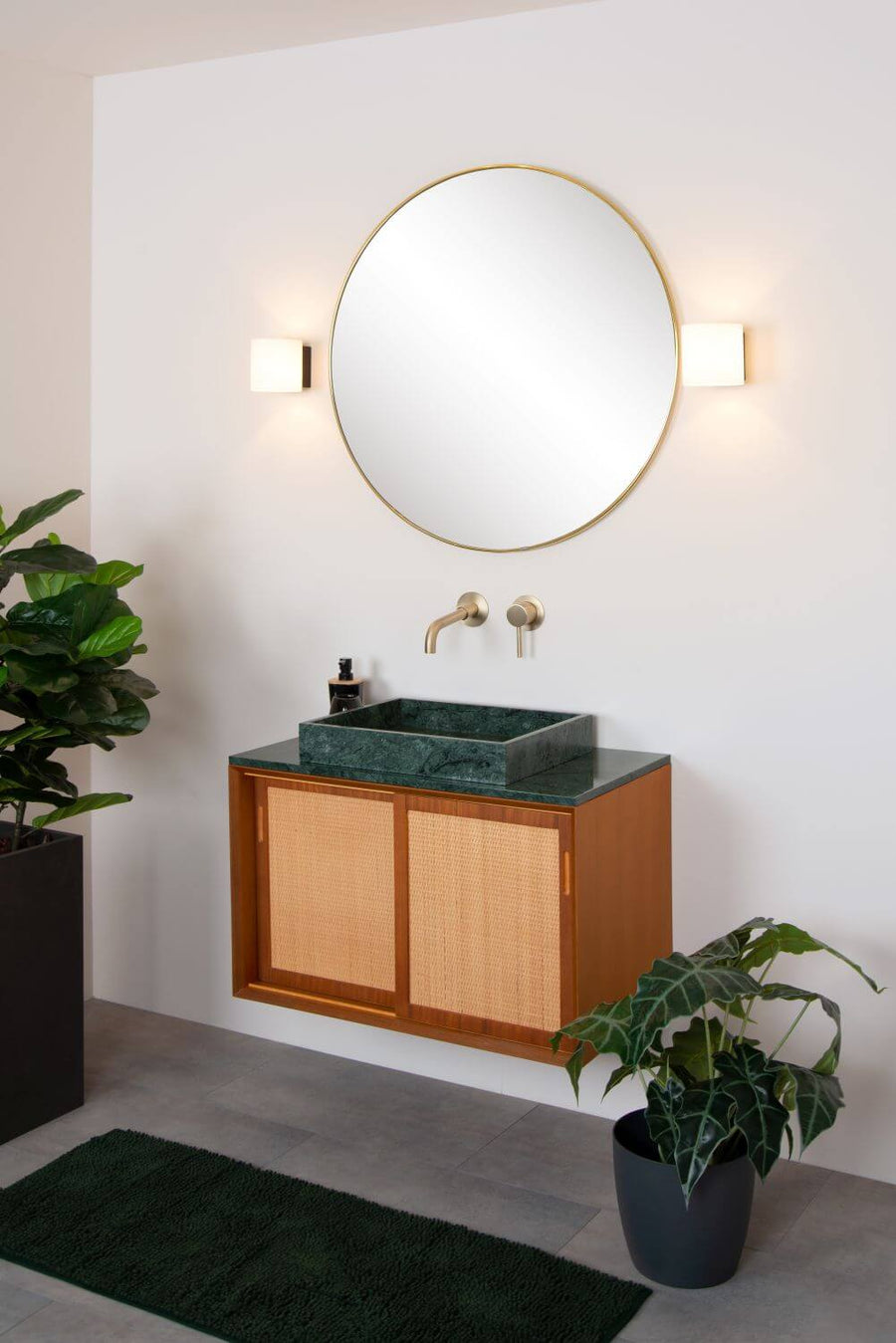 Ambiance complète de la salle de bain avec tapis vert, vasque en marbre et appliques murales