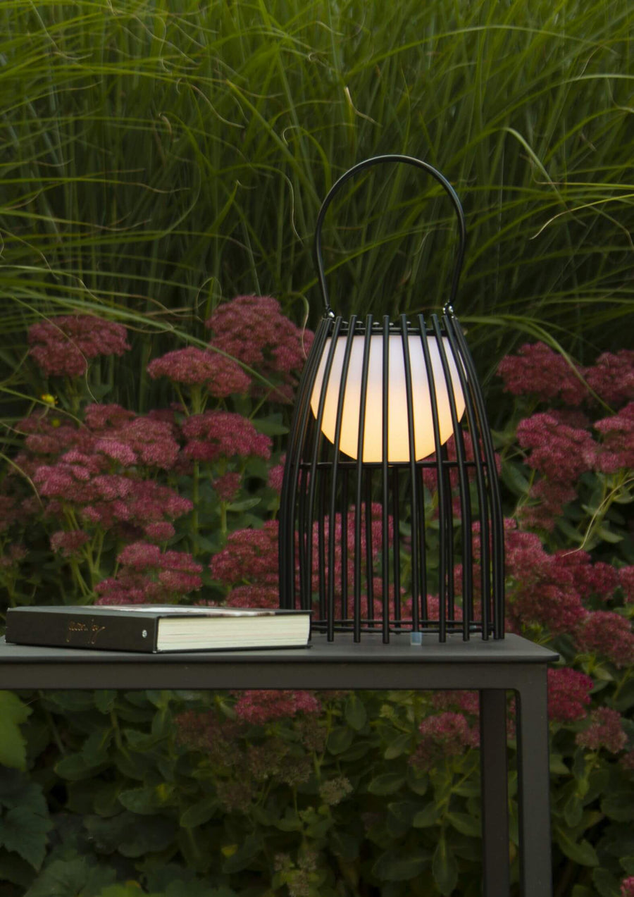 Gros plan de la lampe allumée posée sur une table, avec un livre à côté.