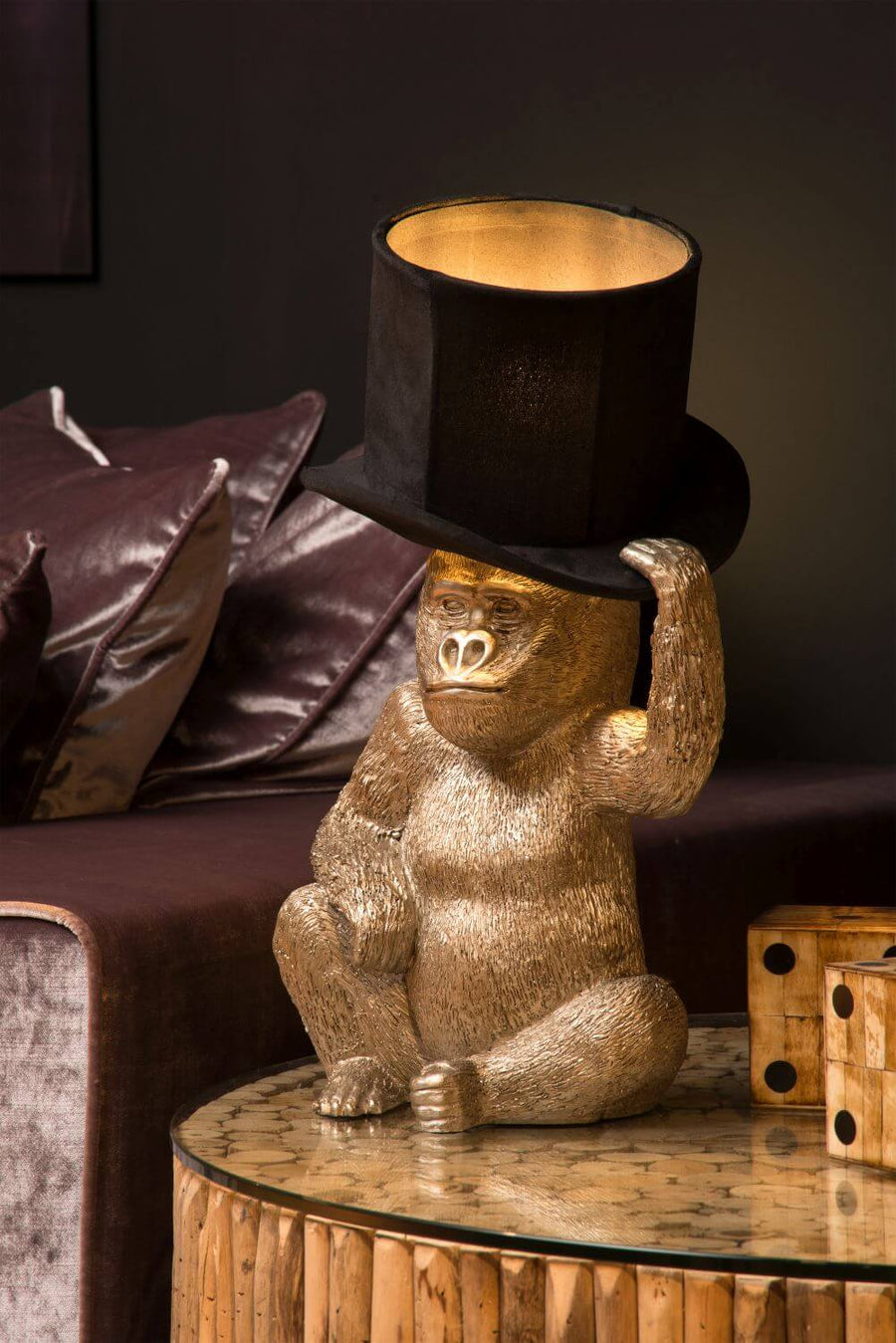 Détail de la finition dorée du singe et de son chapeau noir posé sur une table.