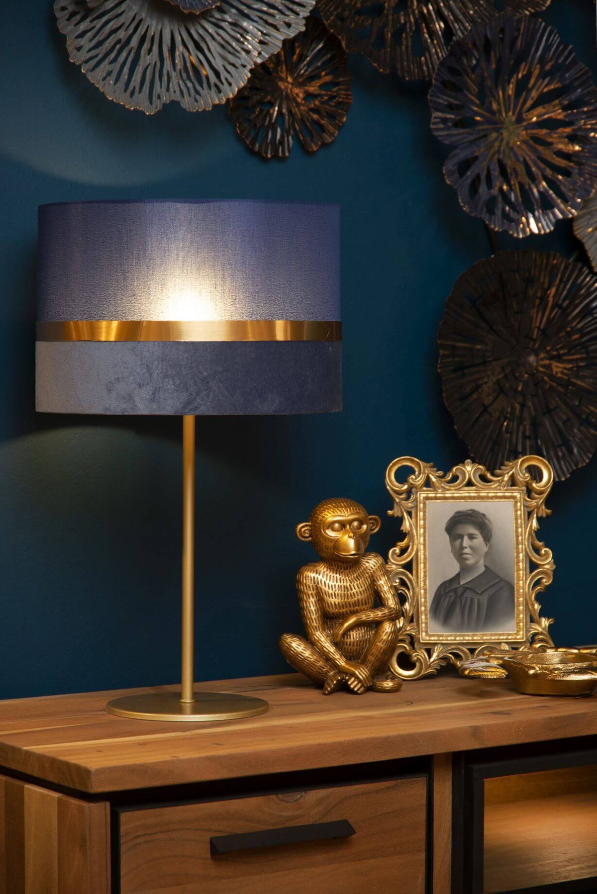 Mise en ambiance avec cadre doré, singe et décoration murale bleue.
