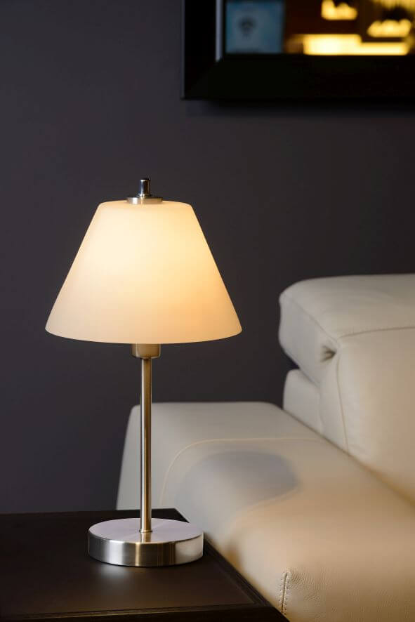 Vue rapprochée de la lampe allumée avec abat-jour blanc et tige chromée