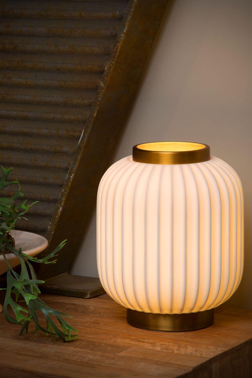 Lampe allumée en ambiance, près d'une plante verte et d'une structure métallique inclinée
