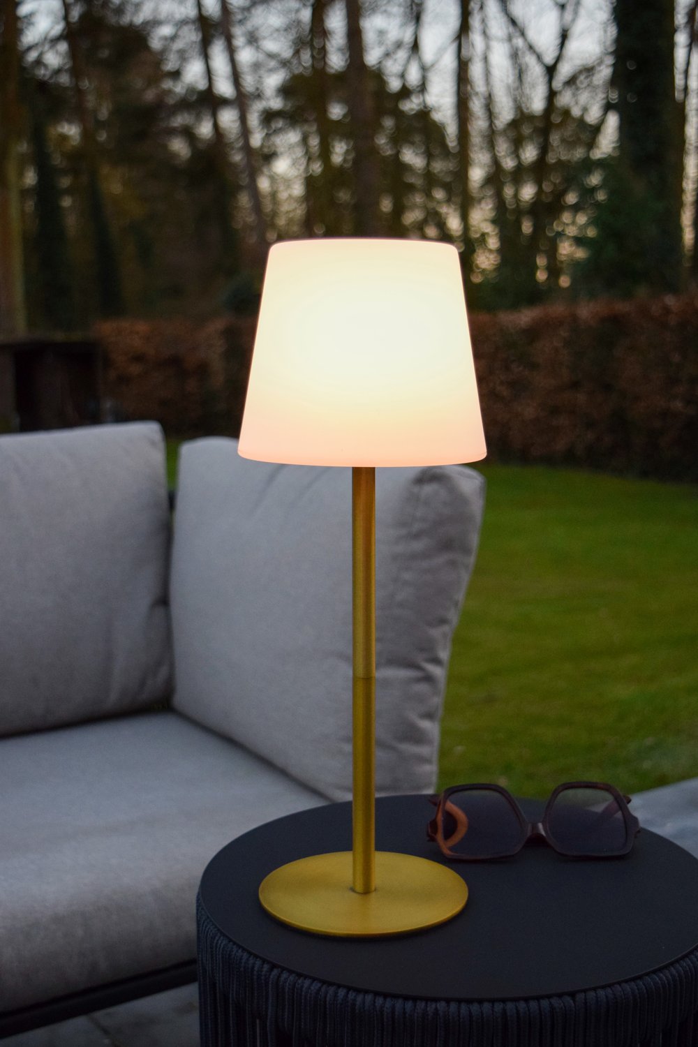 Mise en ambiance extérieure sur table basse, près d'un canapé et lunettes