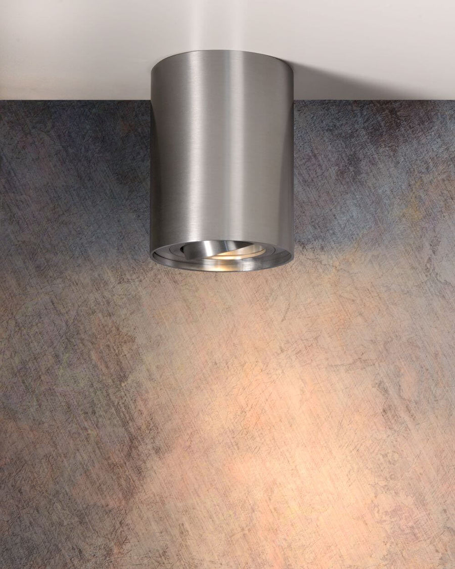 Spot lumineux allumé projetant un faisceau chaud sur un mur à la texture grise