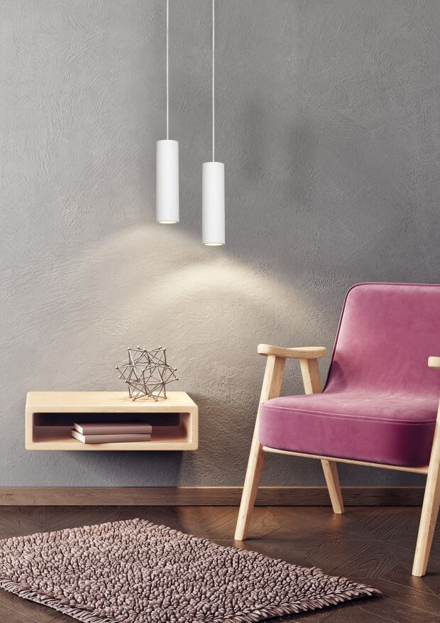 Vue rapprochée de deux suspensions blanches au-dessus d'une table d'appoint et d'un fauteuil rose.