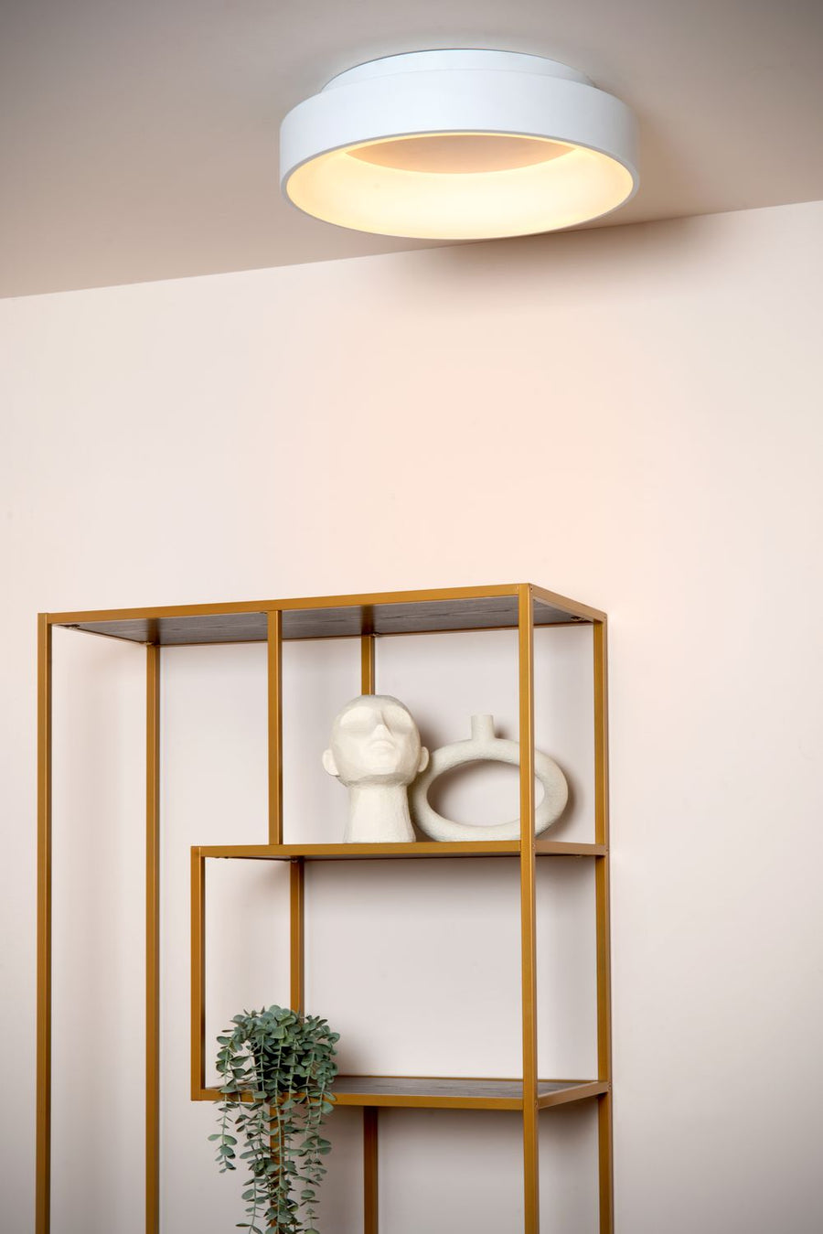 Vue rapprochée du plafonnier blanc allumé, diffuseur rond et halo lumineux chaleureux