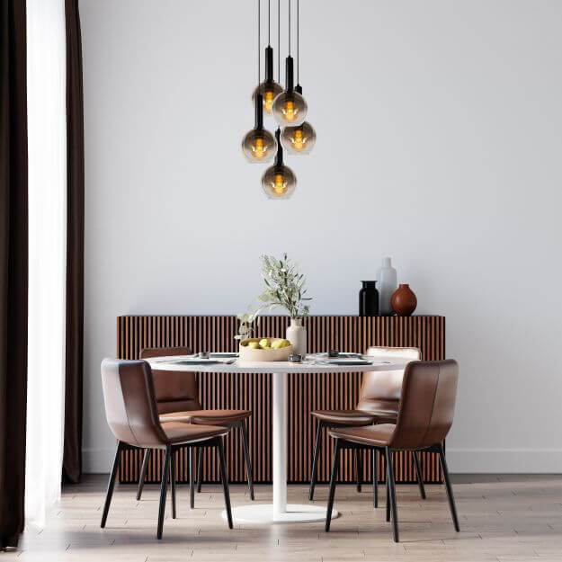 Suspension noire éclairée dans un intérieur clair avec buffet en bois cannelé
