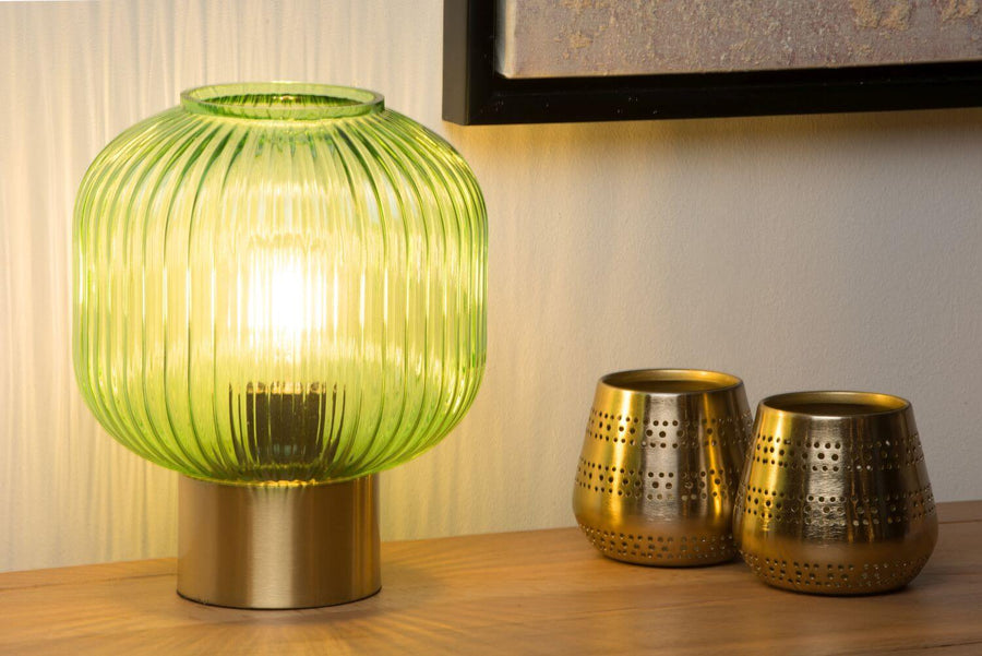 Vue rapprochée du luminaire vert allumé posé sur un meuble en bois clair