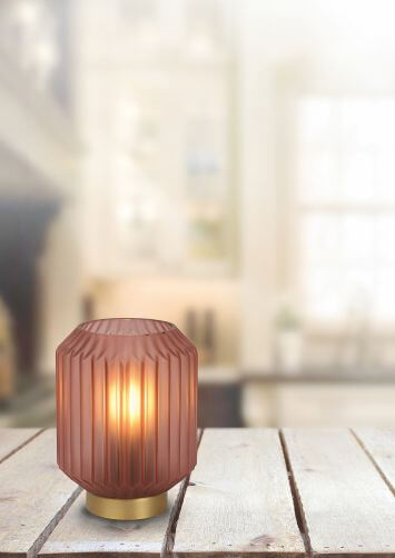 Vue de la lampe allumée posée sur une table, arrière-plan domestique flou et lumineux.