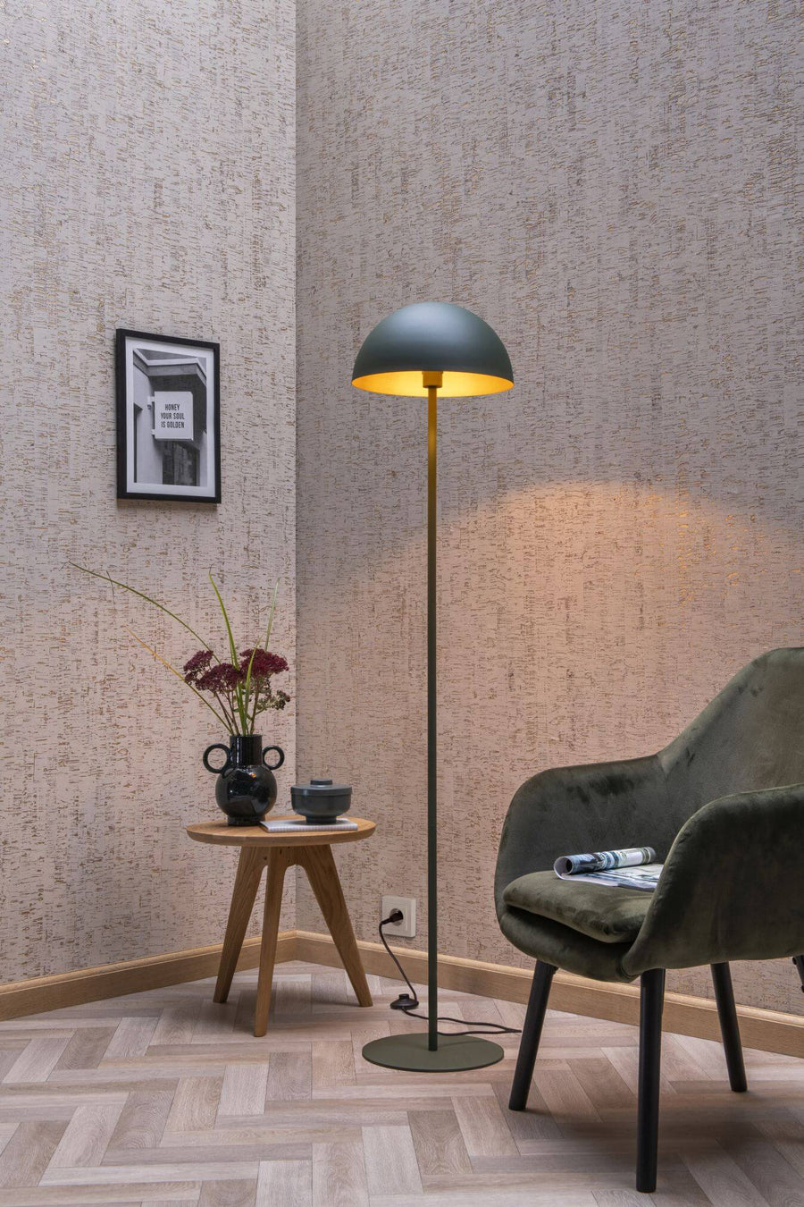 Vue rapprochée du lampadaire vert allumé, abat-jour doré éclairant le mur texturé