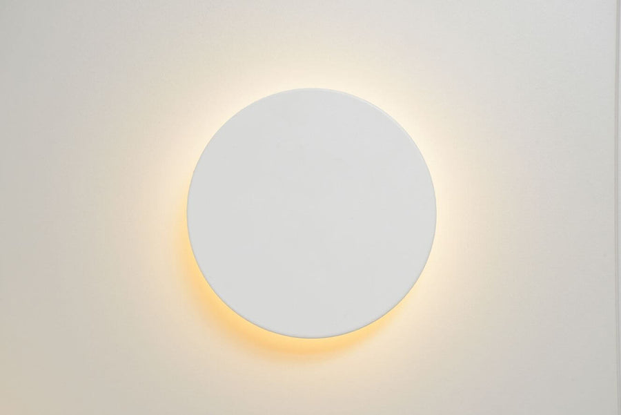 Applique allumée vue de face, lumière indirecte diffuse sur mur beige clair