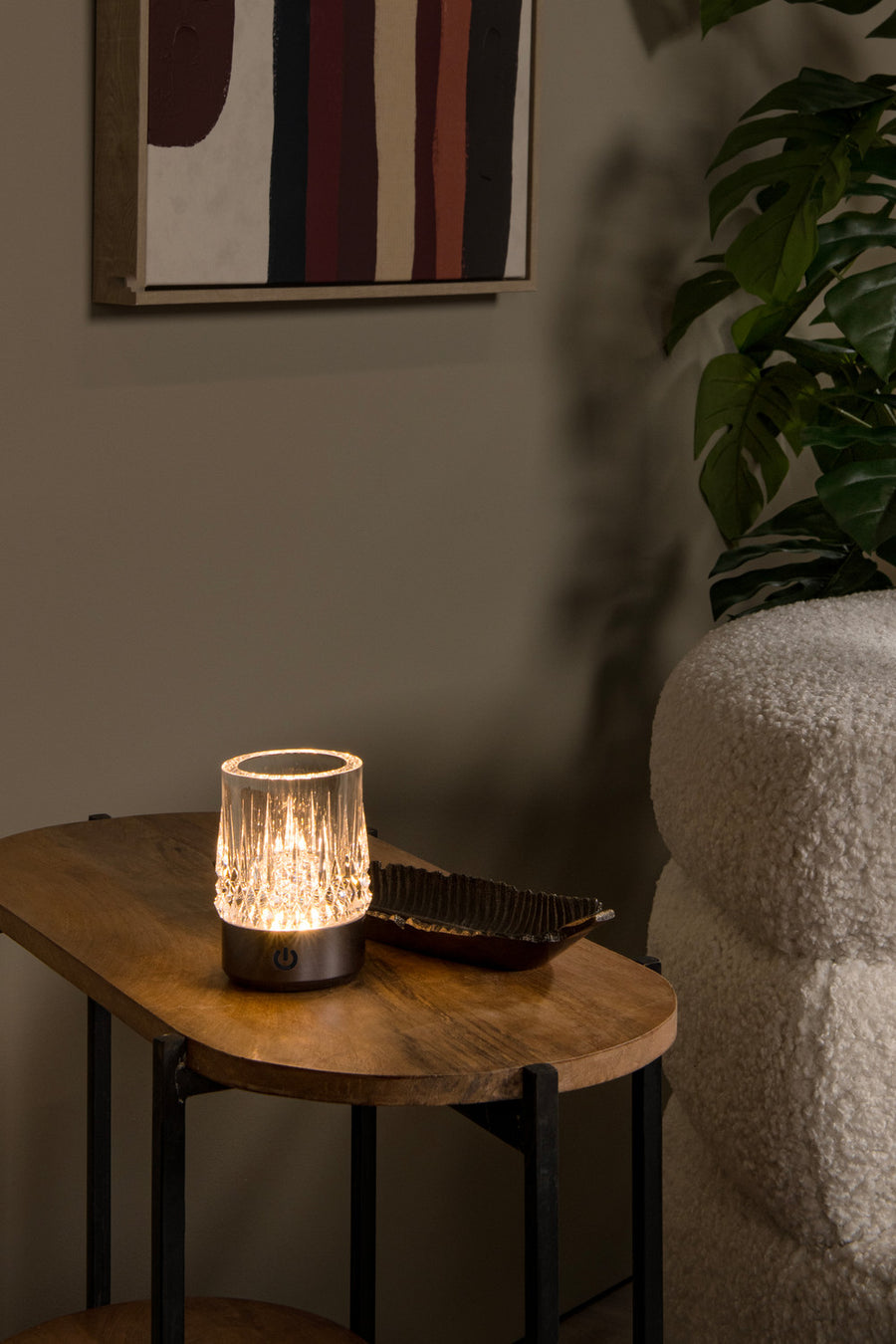 Vue rapprochée de la lampe à poser éclairée sur son support en bois clair
