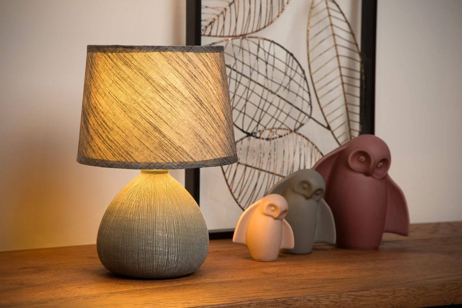Vue large de la lampe allumée sur un meuble, entourée de trois hiboux décoratifs.