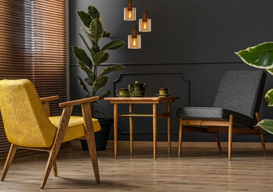 Scène de vie avec deux fauteuils, table en bois et suspension à trois lumières suspendues.
