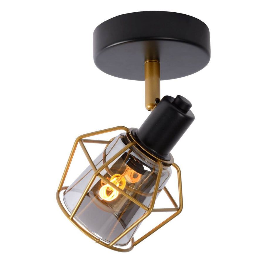 Gros plan sur la cage métallique dorée et le verre fumé du luminaire allumé.