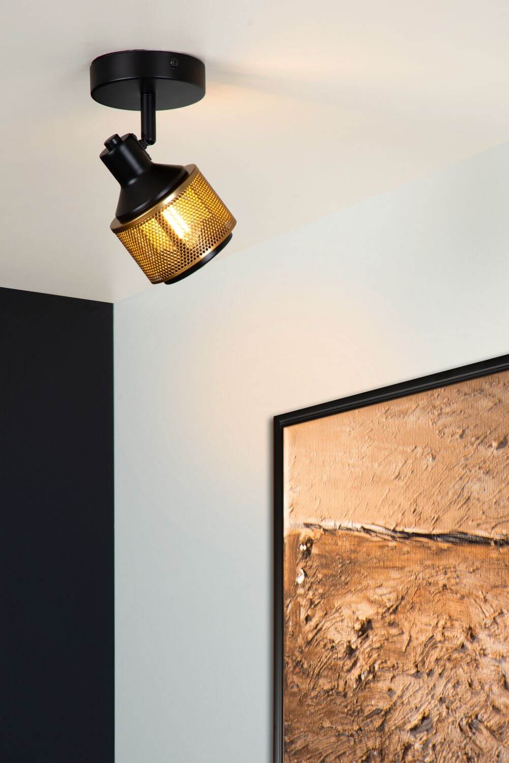 Plafonnier allumé fixé au plafond, éclairant un mur avec tableau encadré.