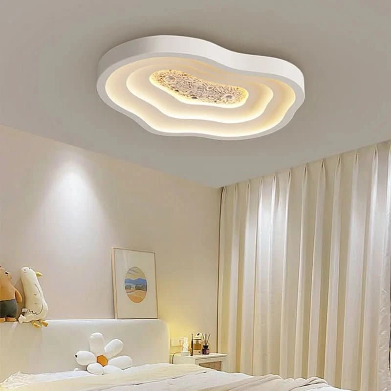 Plafonnier ovale ondulé blanc allumé dans une chambre à la lumière chaude, ambiance douce.