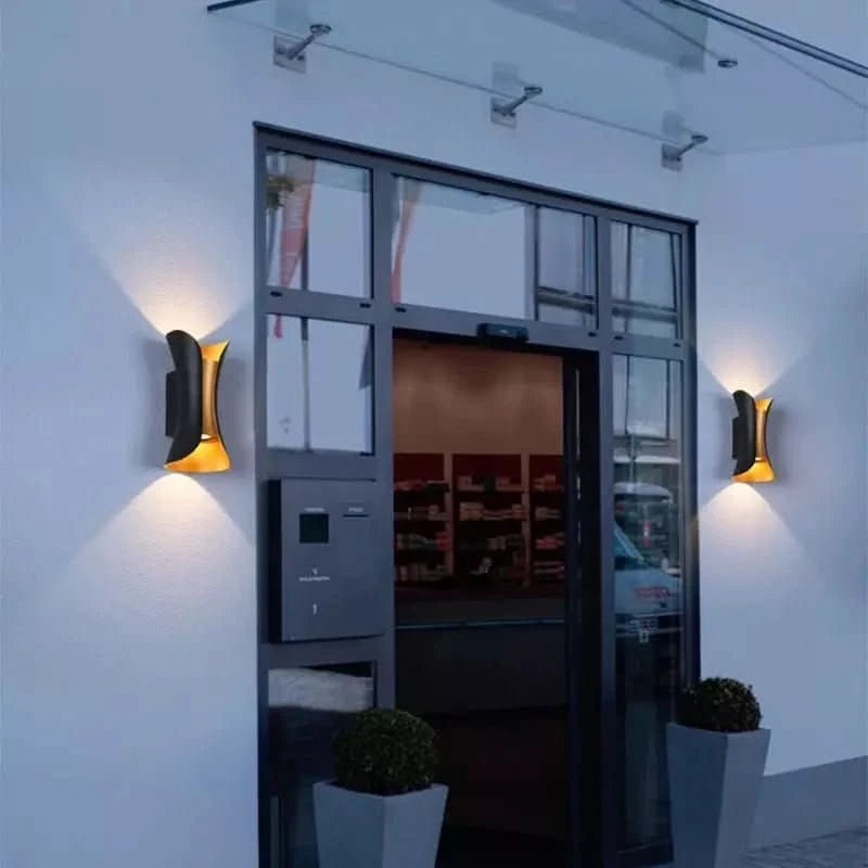 Entrée vitrée avec deux appliques murales noires et dorées allumées de nuit