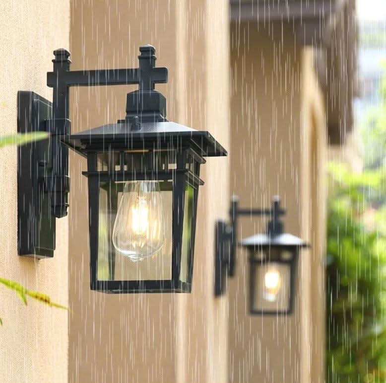 Deux luminaires muraux éclairés sous une pluie battante, illustrant la résistance aux intempéries