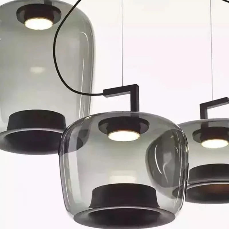 Gros plan sur trois suspensions en verre fumé et leurs douilles noires intégrées.