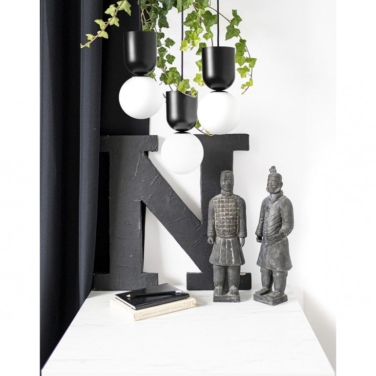 Mise en ambiance avec lierre, lettres décoratives et statuettes devant mur blanc