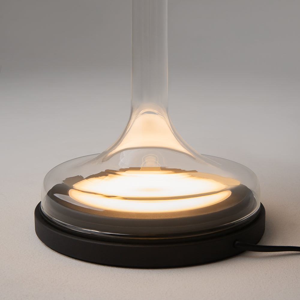 Détail du pied, verre transparent évasé sur socle noir avec anneau lumineux chaud