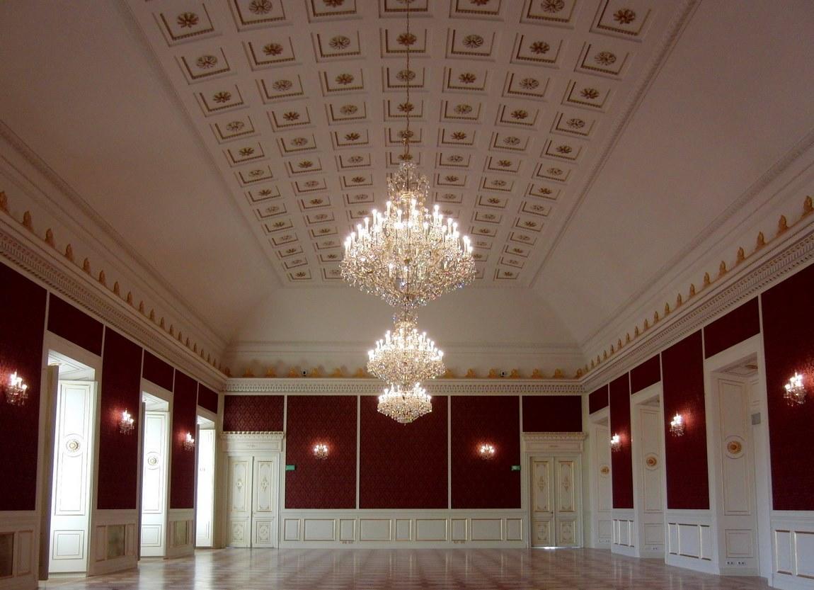 Vue large du plafond à caissons et des trois lustres alignés dans la salle