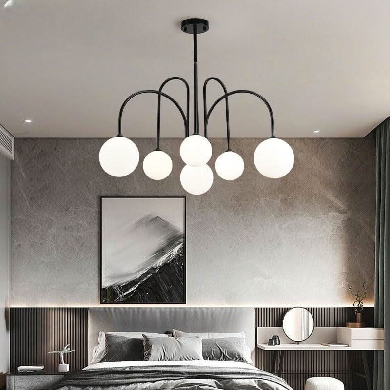 Lustre noir à six globes blanches suspendu dans une chambre, lit gris et coiffeuse murale.