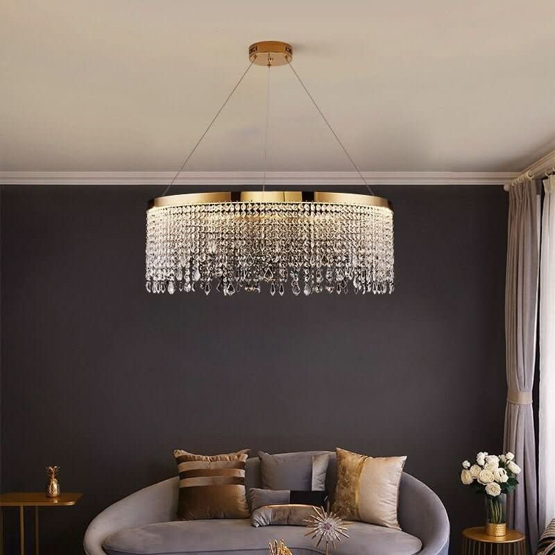 Lustre rond doré à pampilles de cristal suspendu au-dessus d'un canapé gris