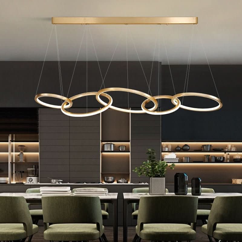 Luminaire doré à anneaux fins suspendu au-dessus d'un comptoir de cuisine moderne